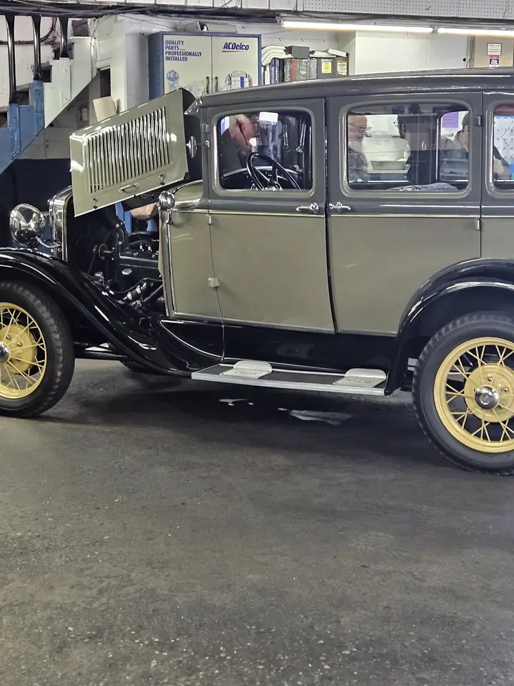 A vintage sedan with spoked wheels inside a KC Martin service bay