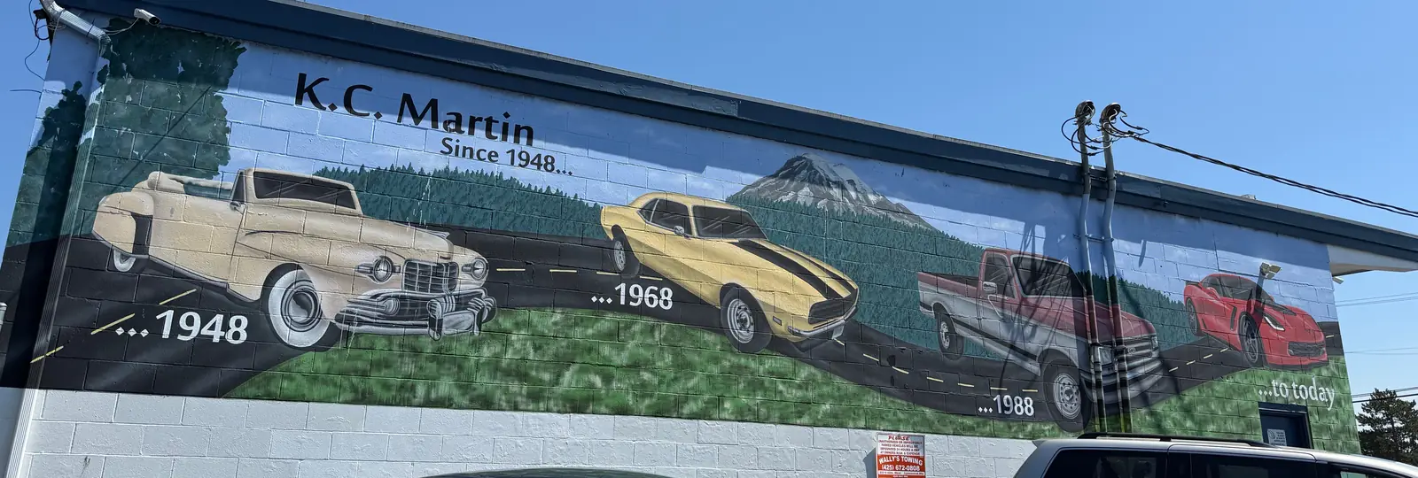 The mural on the side of the KC Martin shop: cars from 1948, 1968 and 1988 to today under the words K.C. Martin, Since 1948